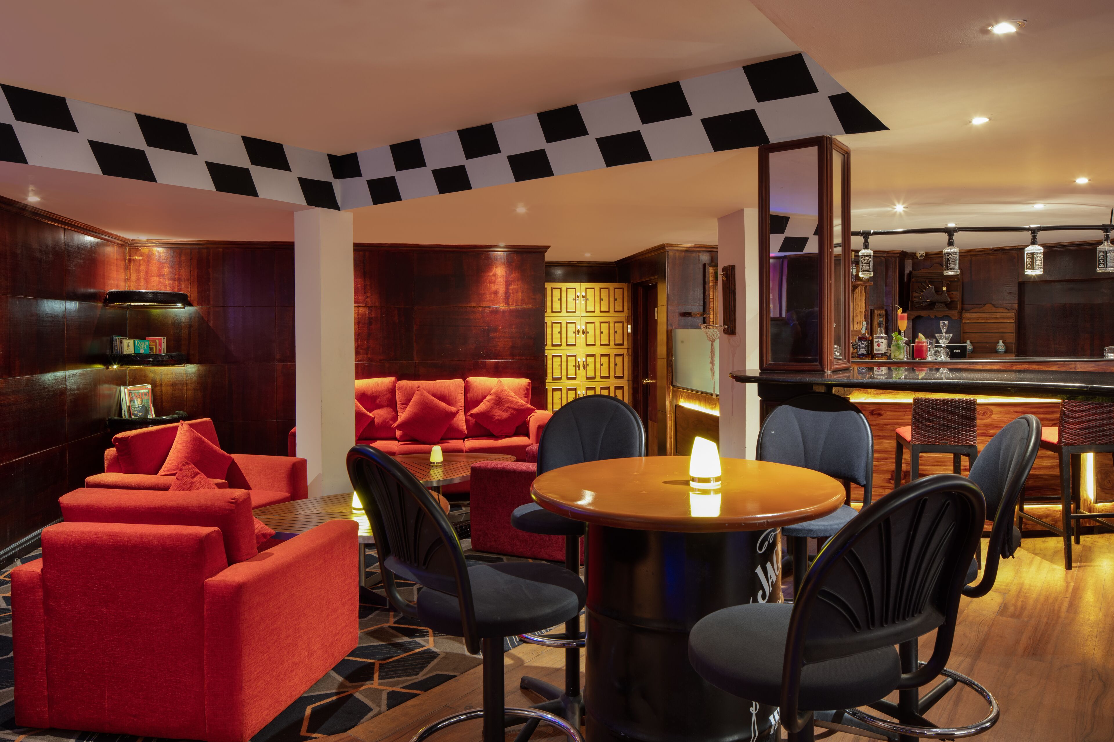 A modern lounge area with red sofas, a round wooden table, and black chairs.