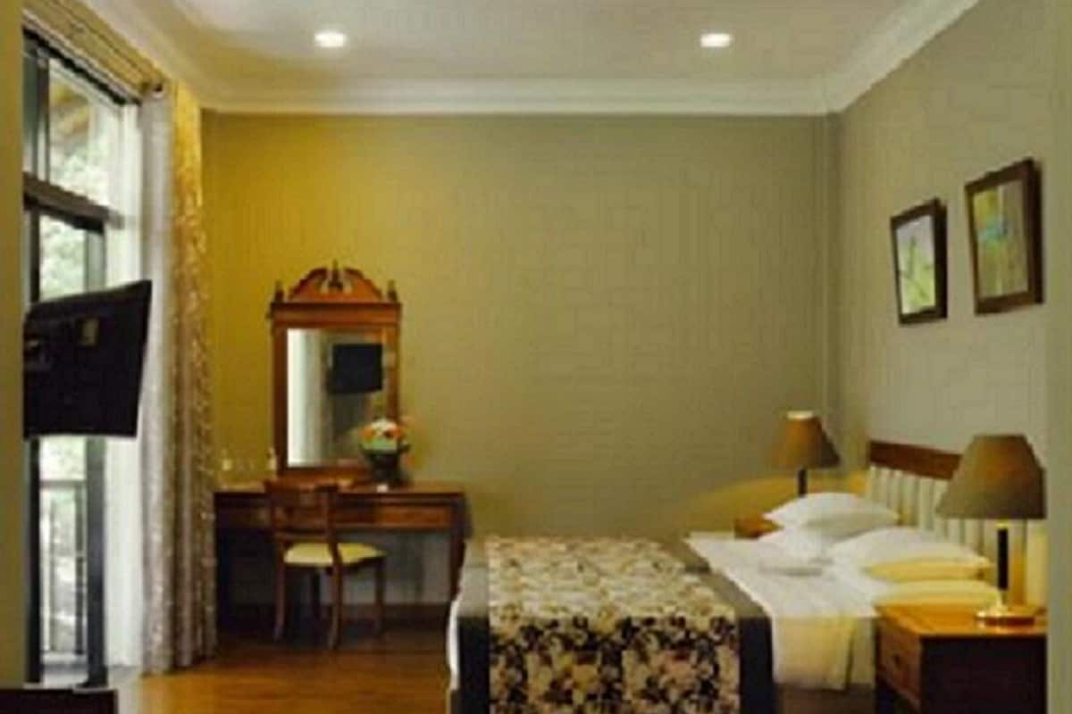 Una habitación de hotel con una cama, un escritorio, una silla, un espejo y una ventana.