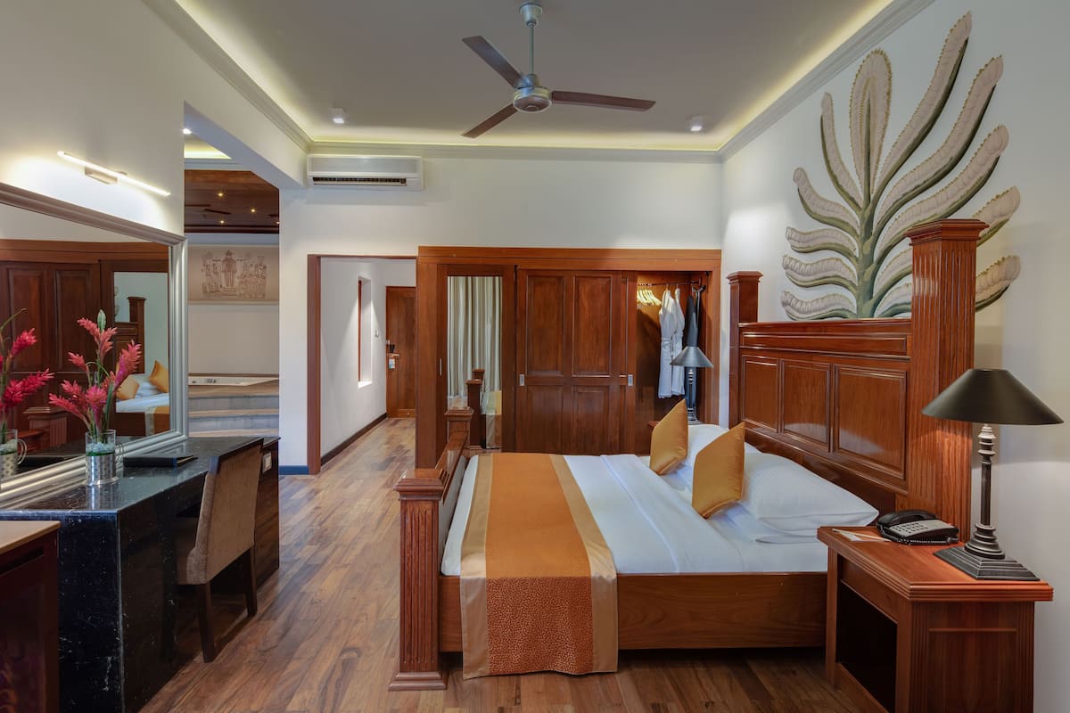 Una habitación de hotel con cama, escritorio, silla, lámpara y espejo.