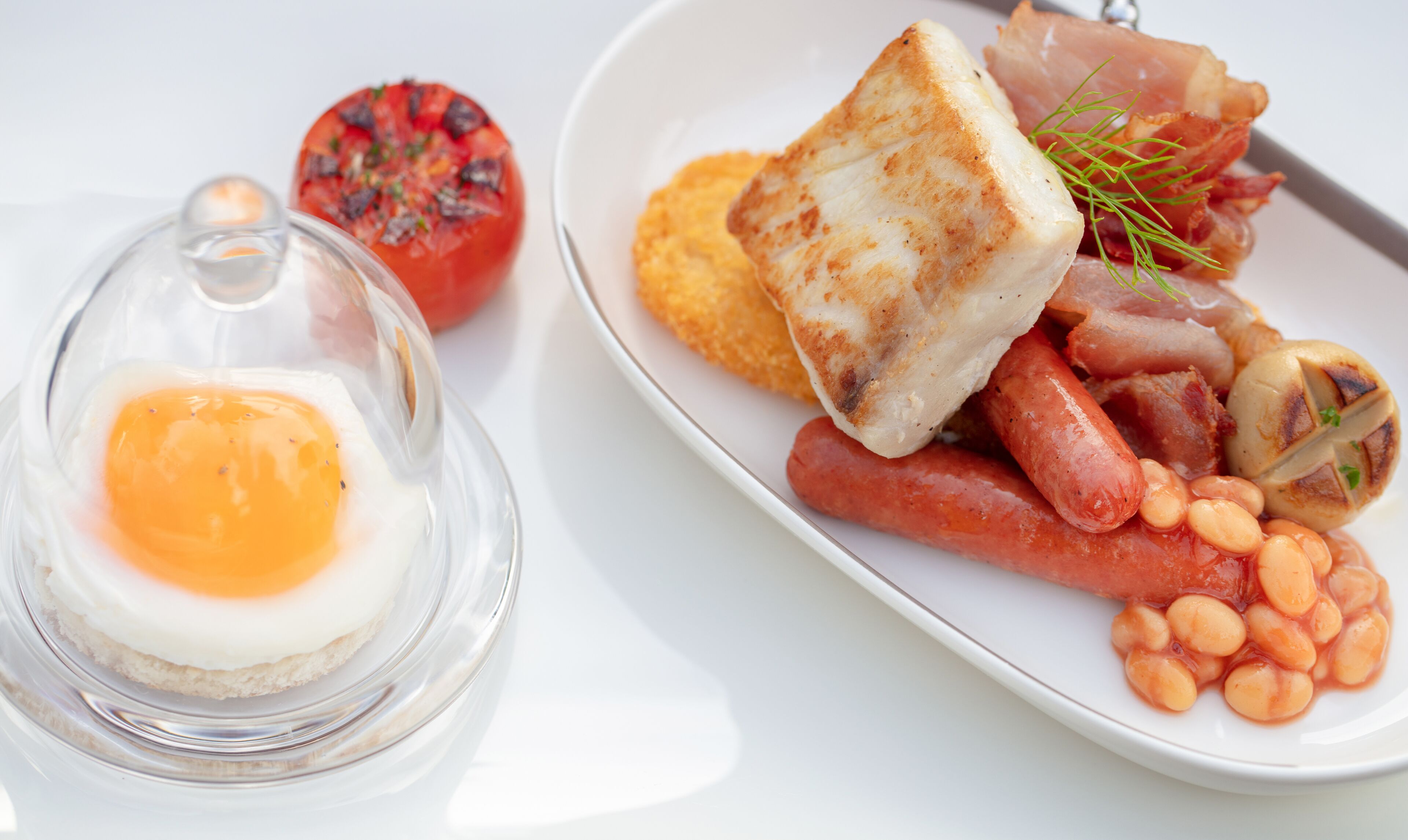 Un plato de desayuno con huevos, salchichas, champiñones y frijoles.