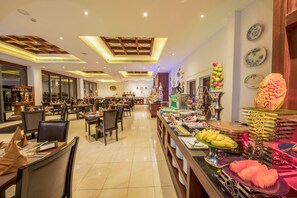 Un comedor amplio con varias mesas y sillas, un bufé con distintos alimentos, y decoración en las paredes.