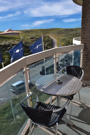 A balcony with a round table and two chairs, overlooking a road and a hilly landscape. - Fletcher Hotel-Restaurant Zeeduin (Wijk aan Zee)