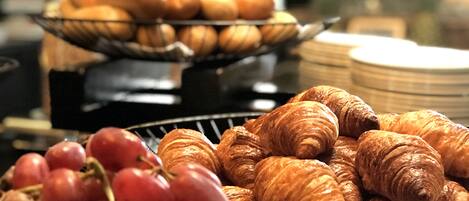 Un bufé con croissants y uvas.