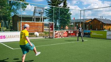 A soccer field with a goal net, a player in a yellow jersey, and another player in a black jersey.