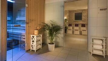 A spa area with wooden walls, a potted plant, and a relaxation room with chairs and towels.