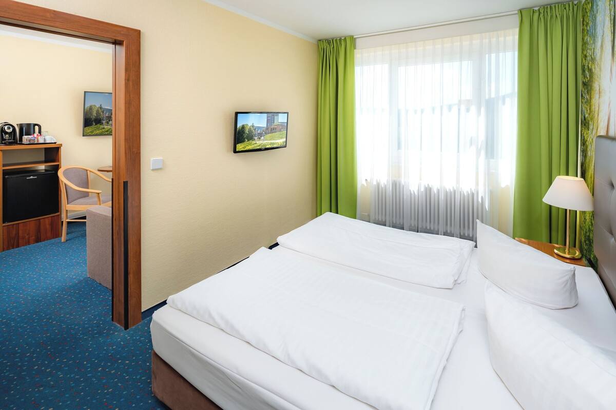Une chambre d’hôtel comprenant un lit, un bureau avec un ordinateur, une chaise et un téléviseur.