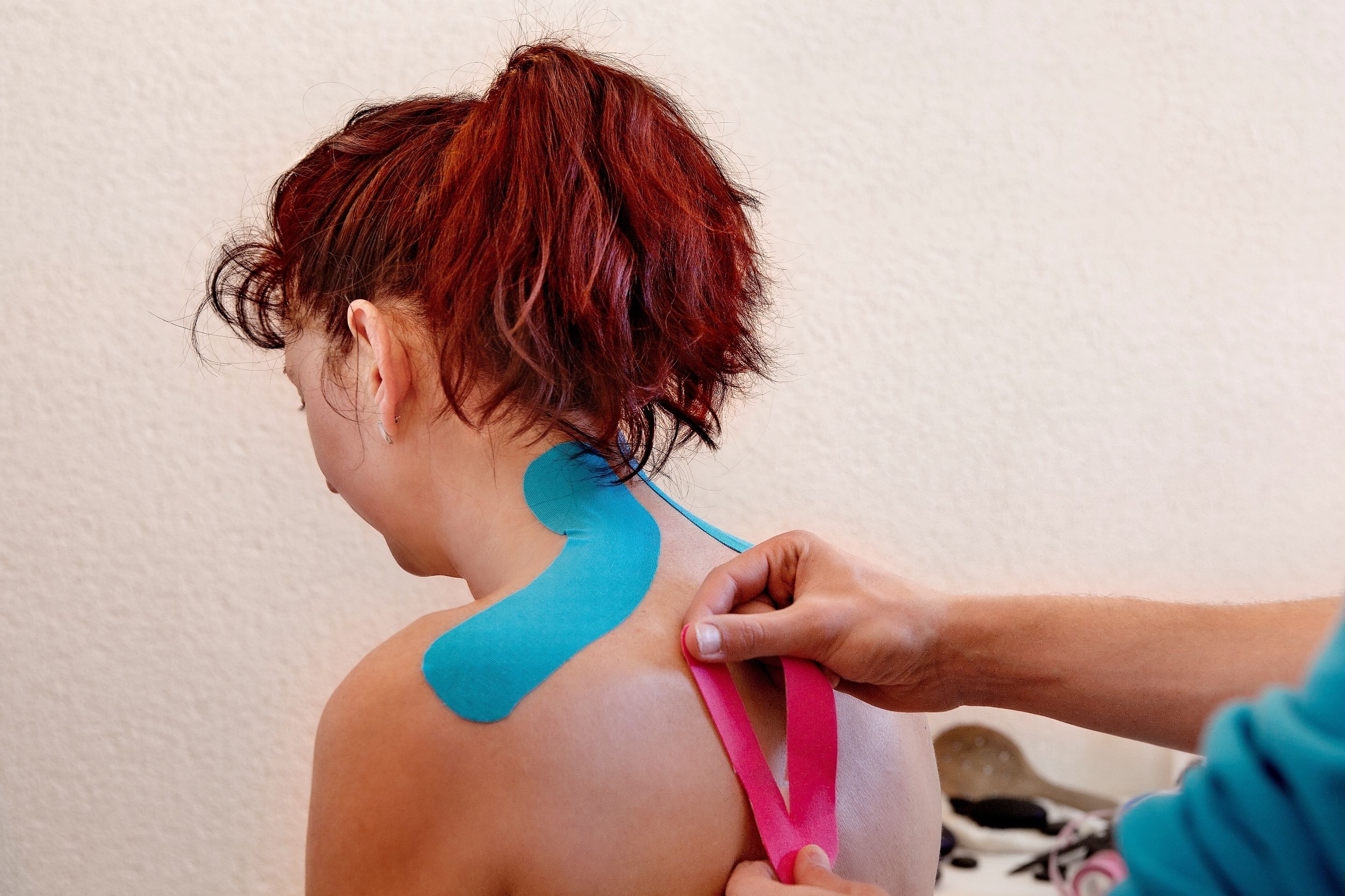 Iemand ontvangt een medische behandeling met blauwe en roze pleister op de rug.