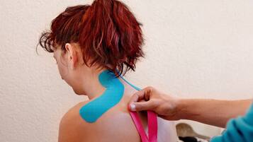 A person receiving a medical procedure with a blue and pink tape applied to their back.