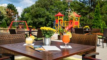 Enjoy a meal al fresco in a serene park-like setting surrounded by lush greenery and a playground.