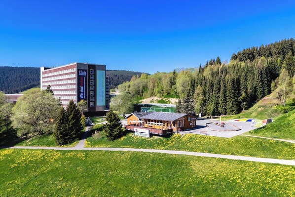 A hotel with a modern building, a wooden lodge, and a sports field.