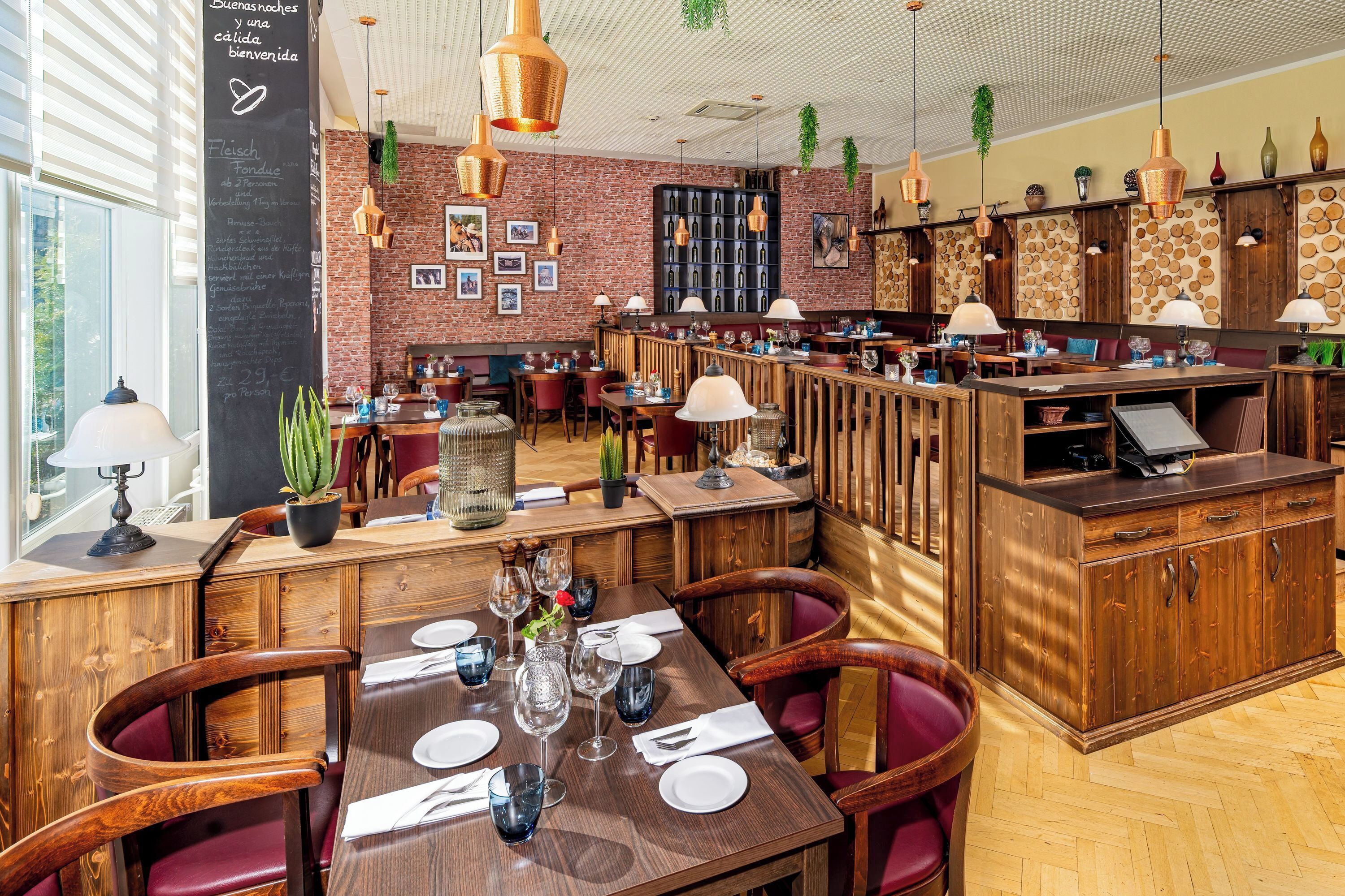 A restaurant with wooden furniture, a chalkboard menu, and hanging plants.
