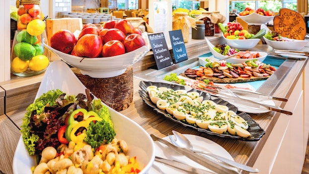 Een buffet met diverse gerechtjes, waaronder fruit, groenten en bereide maaltijden.