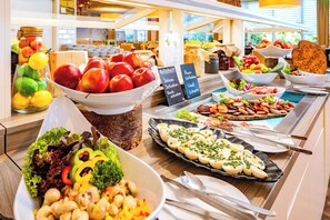 Un buffet proposant une variété de plats, notamment des fruits, des légumes et des plats préparés.
