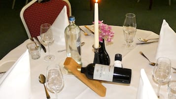 A table set for a meal with a candle, wine glasses, and a bottle of wine.