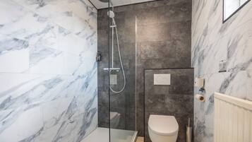 A modern bathroom with a glass-enclosed shower, a toilet, and marble-patterned walls.