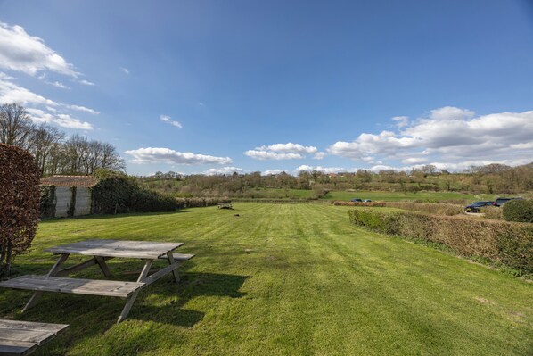 A grassy outdoor area with picnic tables and a small building. - Fletcher Hotel-Restaurant Bon Repos (Noorbeek)