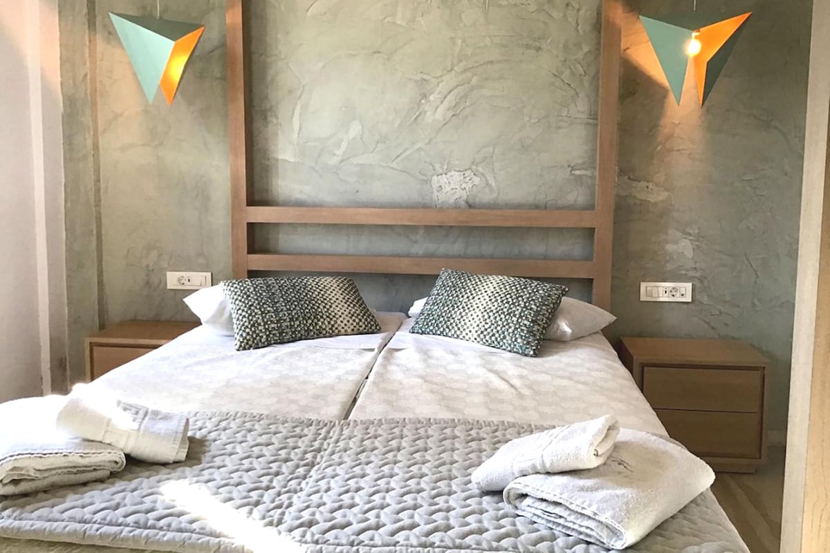 A modern bedroom with a large bed, two nightstands, and a textured wall behind the bed.