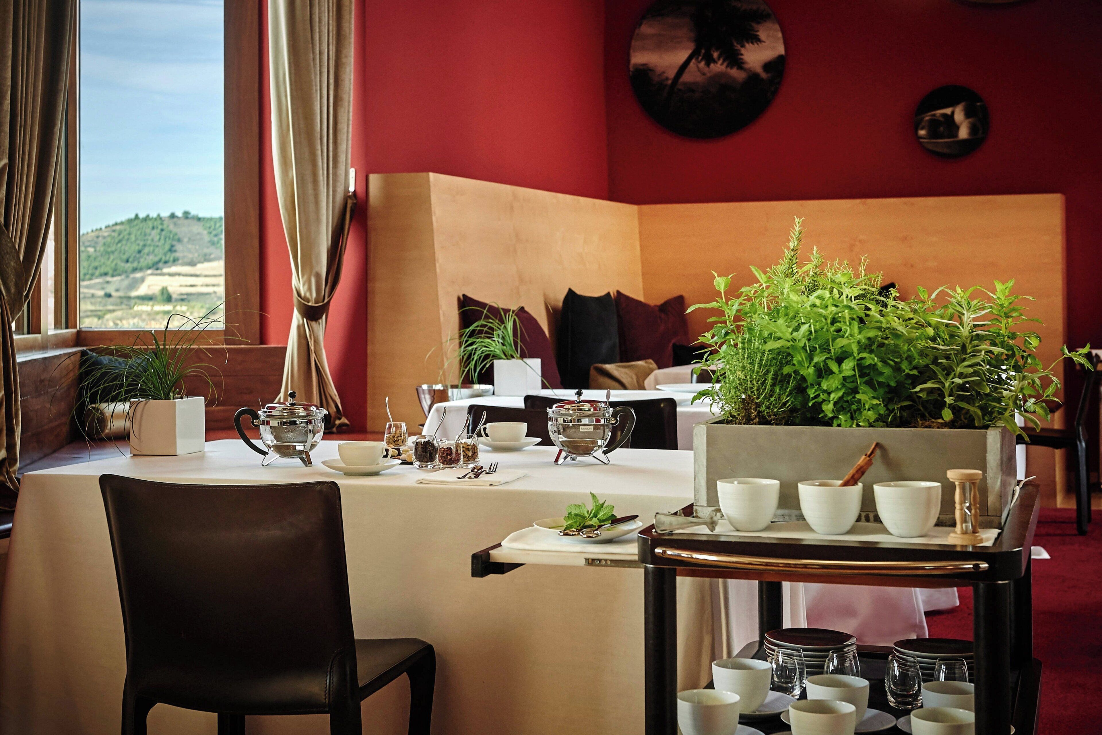 Un comedor con una mesa dispuesta para dos personas, una planta en maceta y vistas al campo.