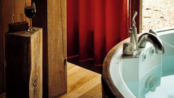 Eine Holzwanne mit Wasserhahn, ein Glas Rotwein und ein roter Vorhang im Hintergrund.