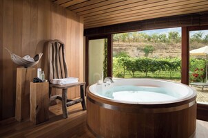Quarto de madeira com banheira de hidromassagem, mobiliário em madeira e vista para vinhedos.