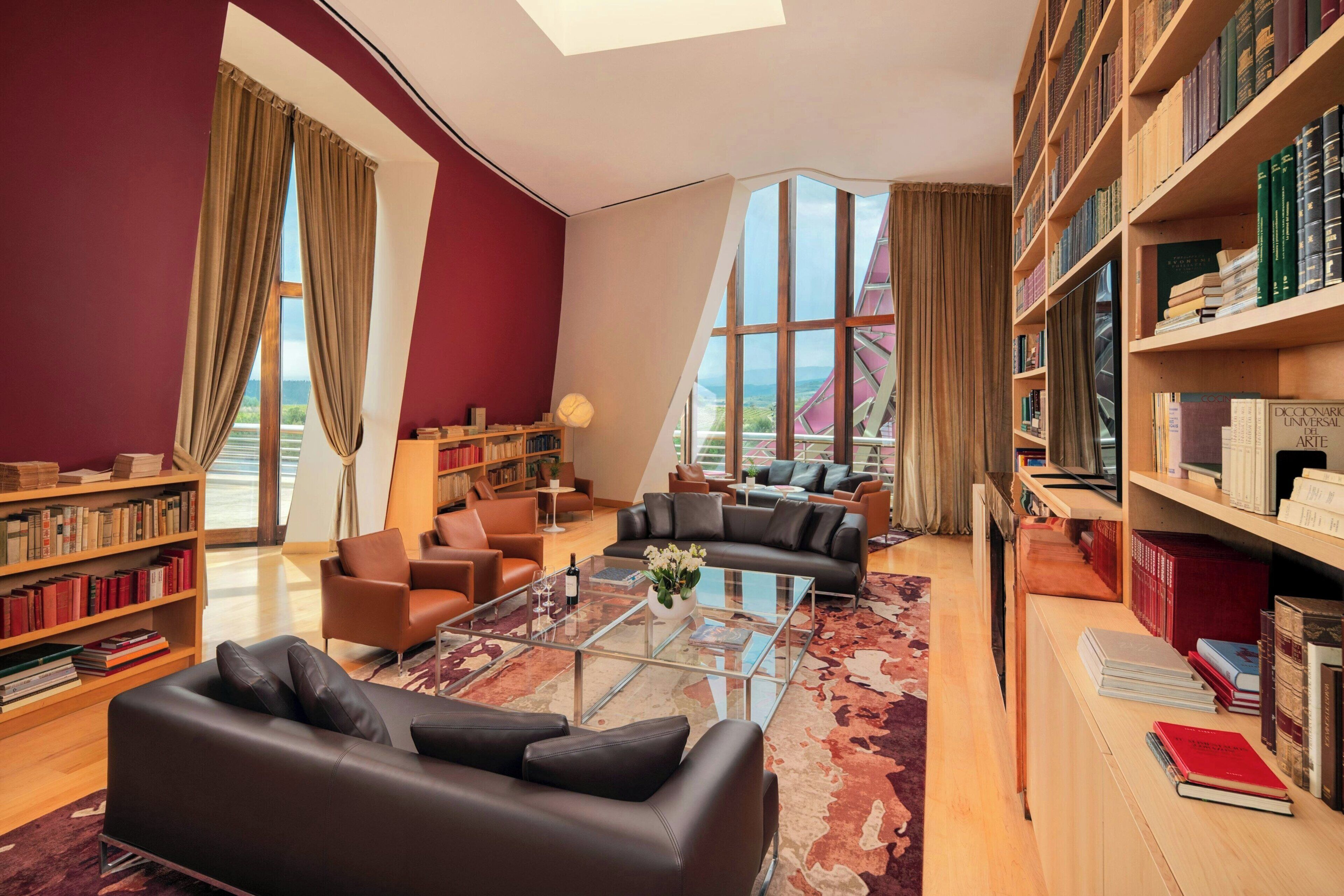 A modern library with leather sofas, a glass coffee table, and bookshelves filled with books.