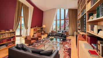 A modern library with leather sofas, a glass coffee table, and bookshelves filled with books.