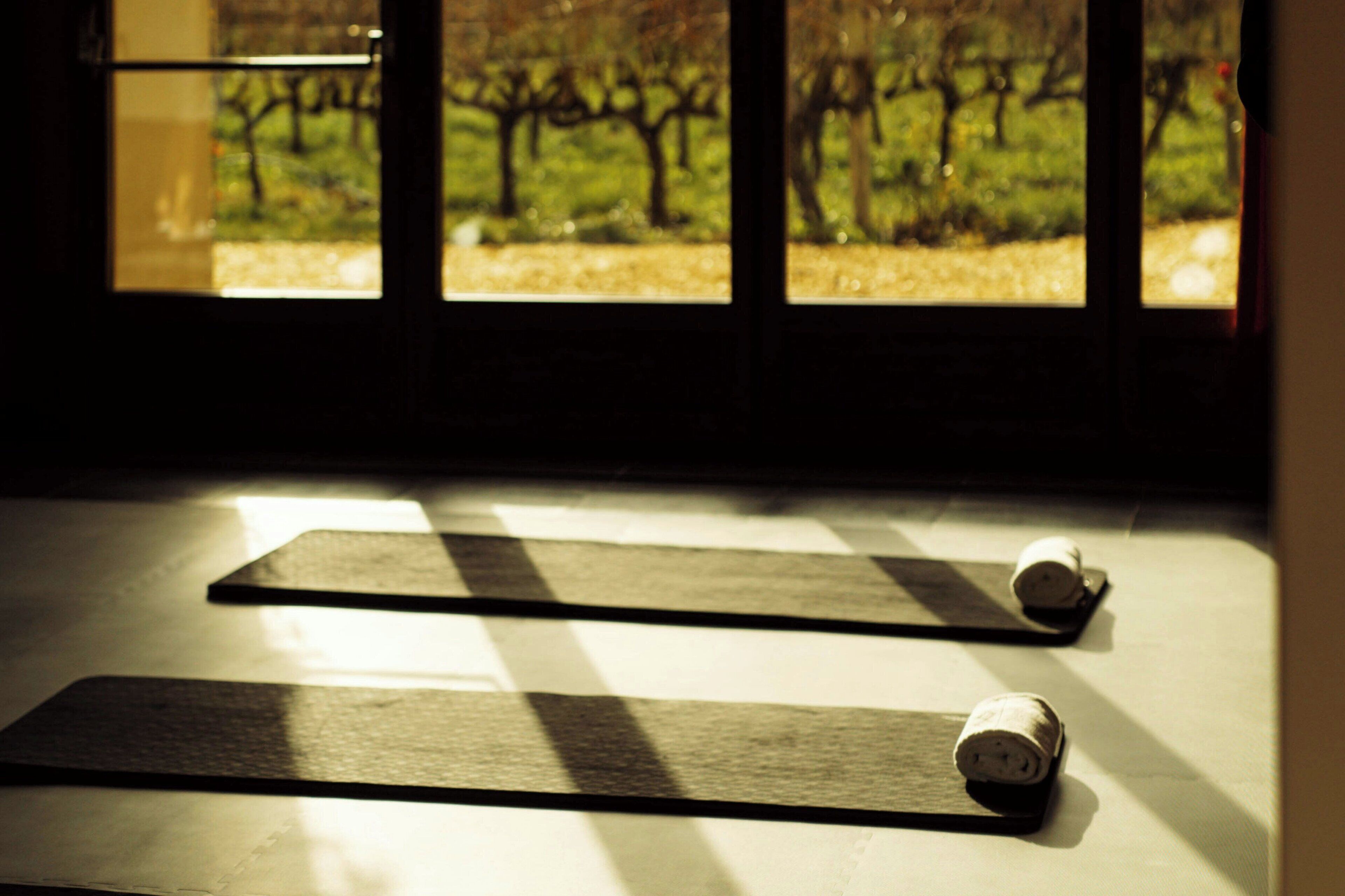 Una habitación con ventanas amplias, suelo a cuadros y una colchoneta de yoga.