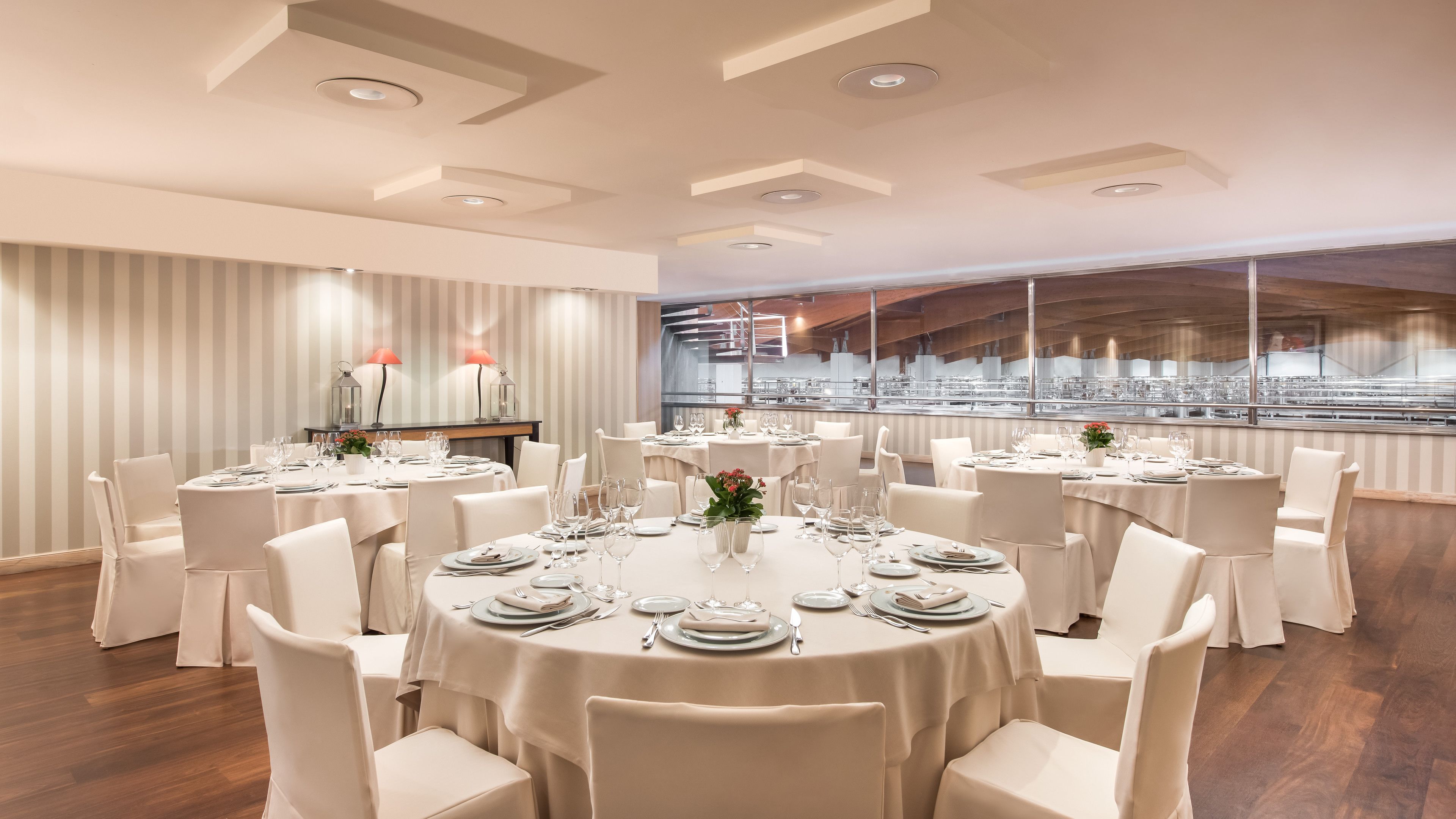 Un vaste espace dédié à la salle à manger, avec des tables rondes, des chaises blanches et un design moderne au niveau du plafond.