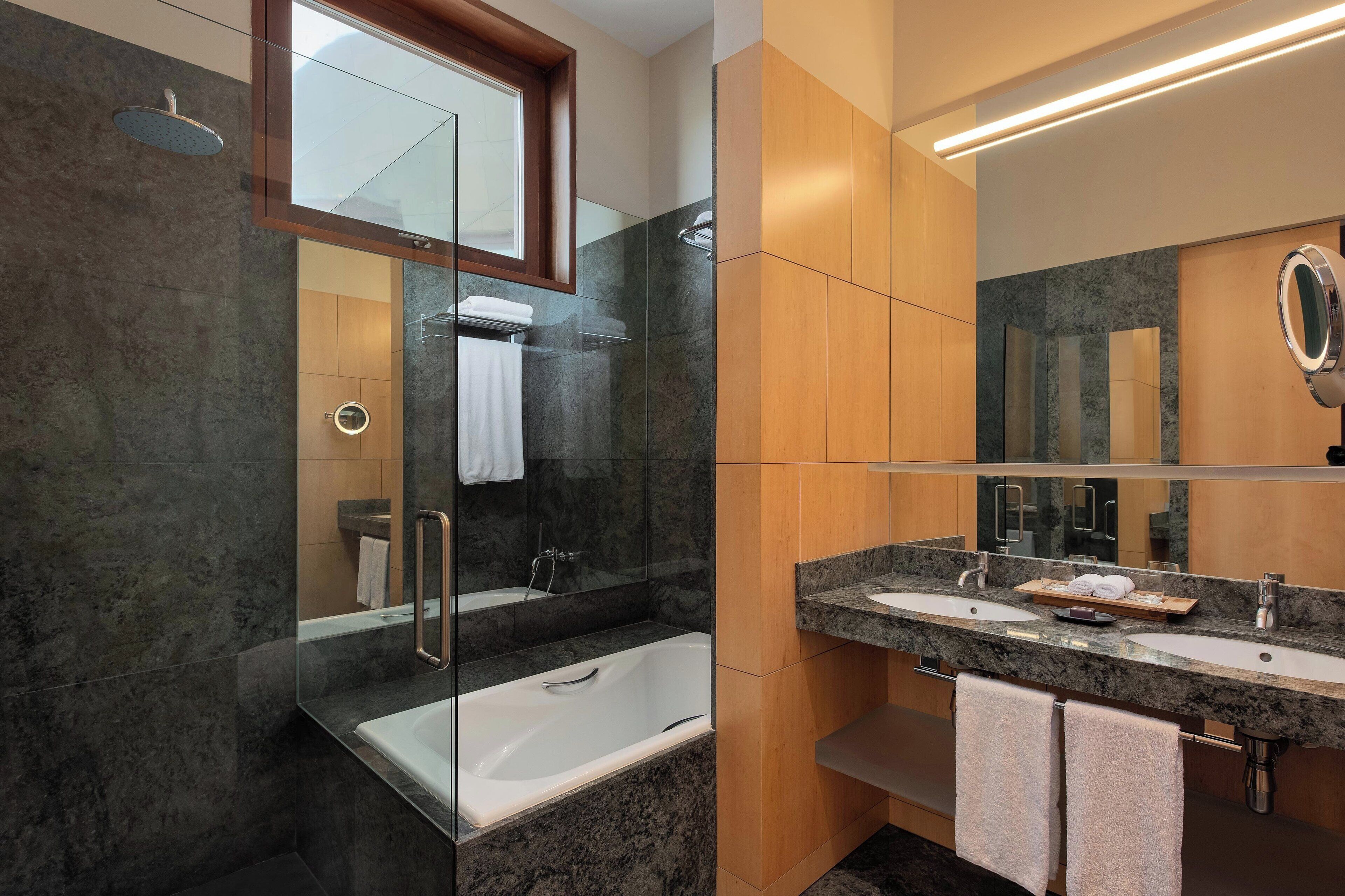Une salle de bain moderne dotée d’une douche à parois de verre, d’une baignoire sur pieds et d’un meuble-lavabo avec deux vasques.