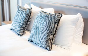 A bed with white bedding and two pillows with a blue and white pattern. - Hampton by Hilton Blackpool (Blackpool)