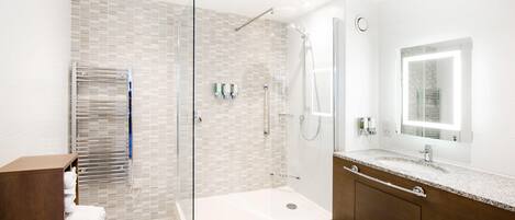 A modern bathroom with a glass-enclosed shower, a vanity with a mirror, and a towel rack.