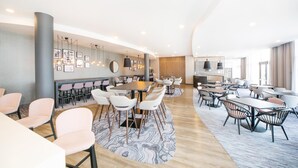 A modern hotel lobby with multiple seating areas, a central dining table, and a large mirror. - Hampton by Hilton Blackpool (Blackpool)