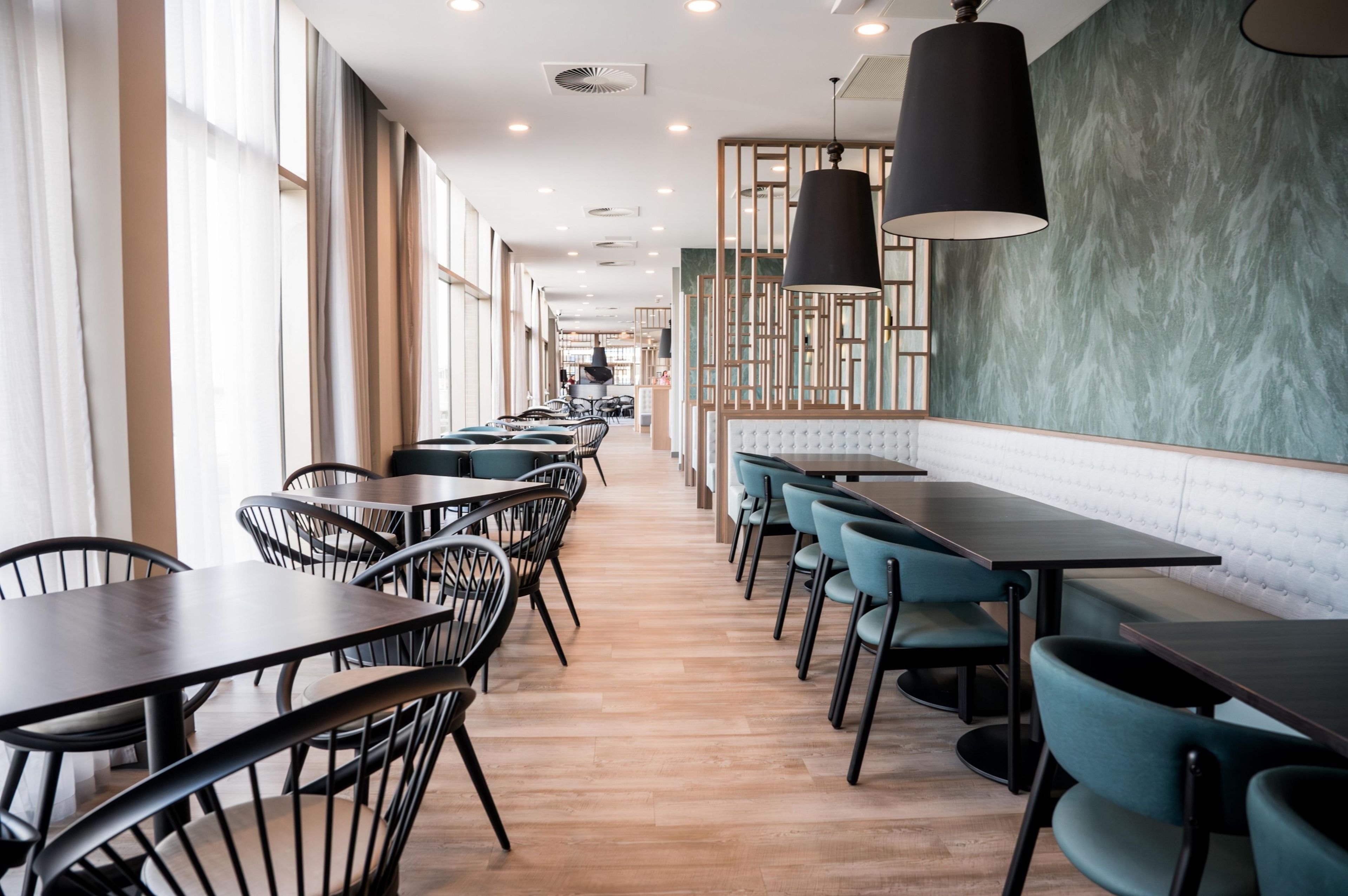 A modern restaurant interior with long tables, chairs, and pendant lighting.