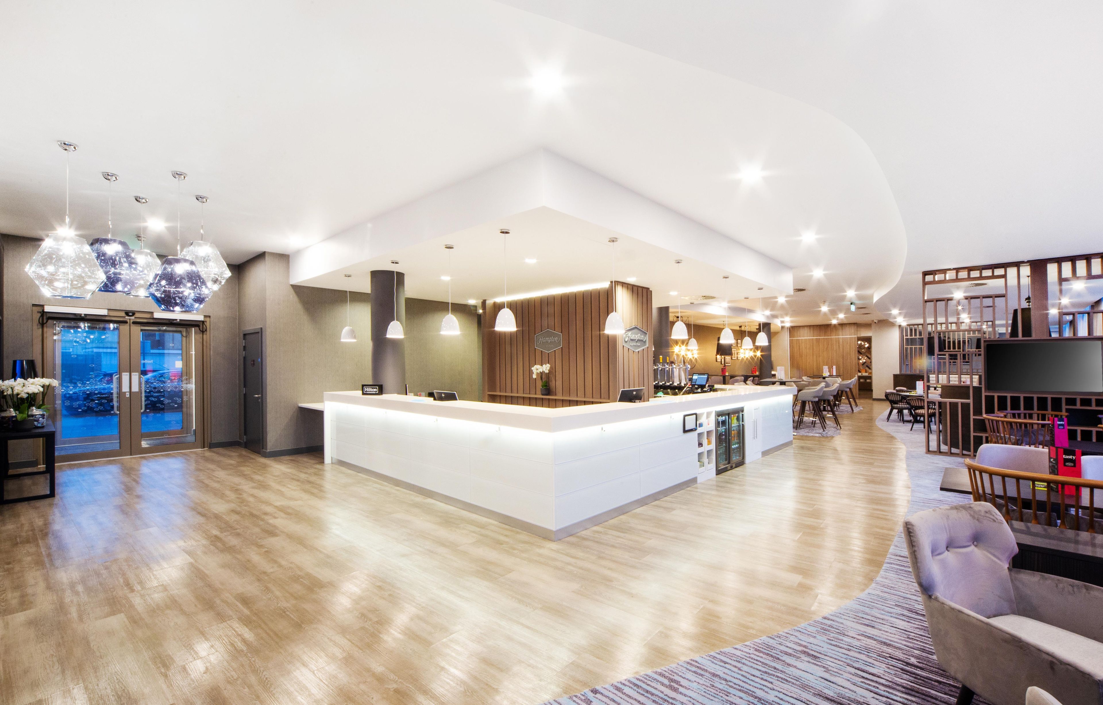 A spacious hotel lobby with a central reception desk, seating area, and a view of the parking garage.