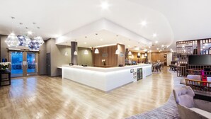 A spacious hotel lobby with a reception desk, seating area, and a large TV screen. - Hampton by Hilton Blackpool (Blackpool)