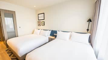 Habitación de hotel con dos camas, una mesita de noche, una lámpara y un cuadro en la pared.