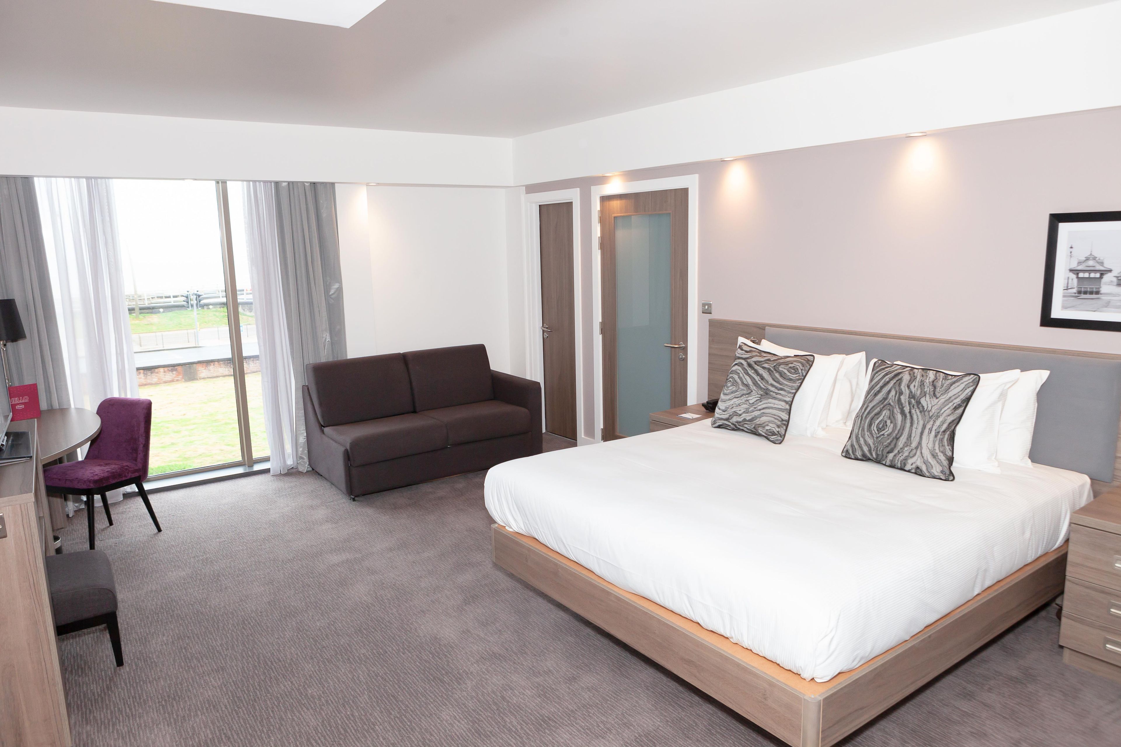 A hotel room with a bed, a sofa, a desk, and a chair.