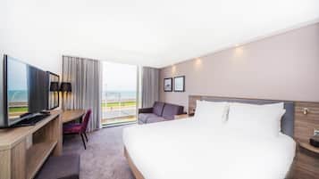 Hotelkamer met een groot bed, een bureau met een computer, een televisie, een stoel en uitzicht op de omgeving.