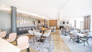 Een moderne hotel lobby met een bar, zitgedeelte en een grote spiegel.