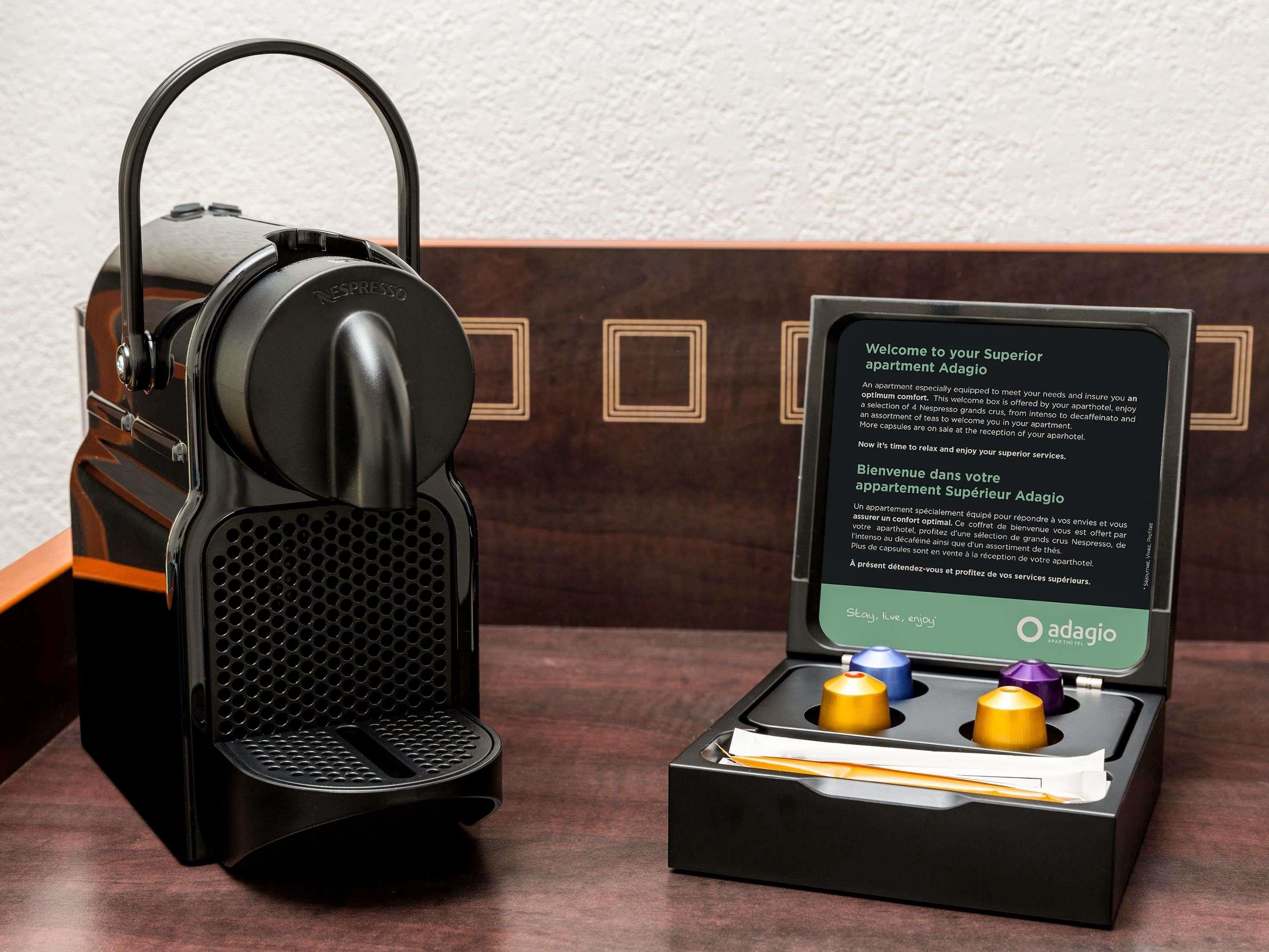 A Nespresso coffee machine with a manual in a box containing two capsules.