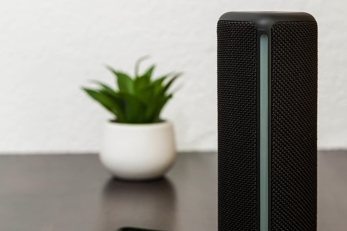 A smartphone on a table with a black speaker beside it.