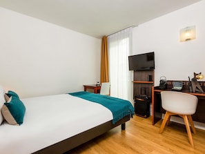 A hotel room with a bed, a desk with a computer, a TV, and a chair. - Aparthotel Adagio Access Paris Porte de Charenton (Charenton-le-Pont)