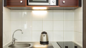 A modern kitchen with a microwave, kettle, and stainless steel sink.