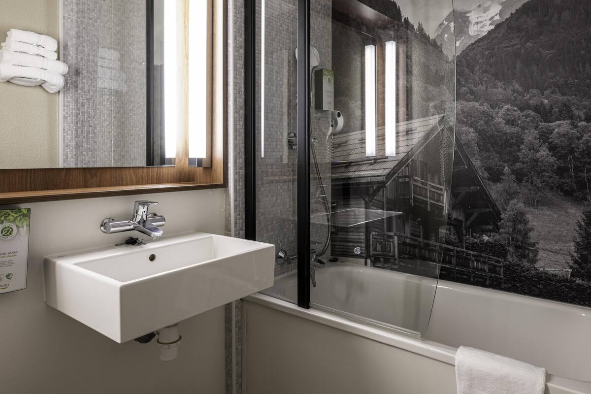 Ein Badezimmer mit Waschbecken, Spiegel und Dusche mit Glastür.