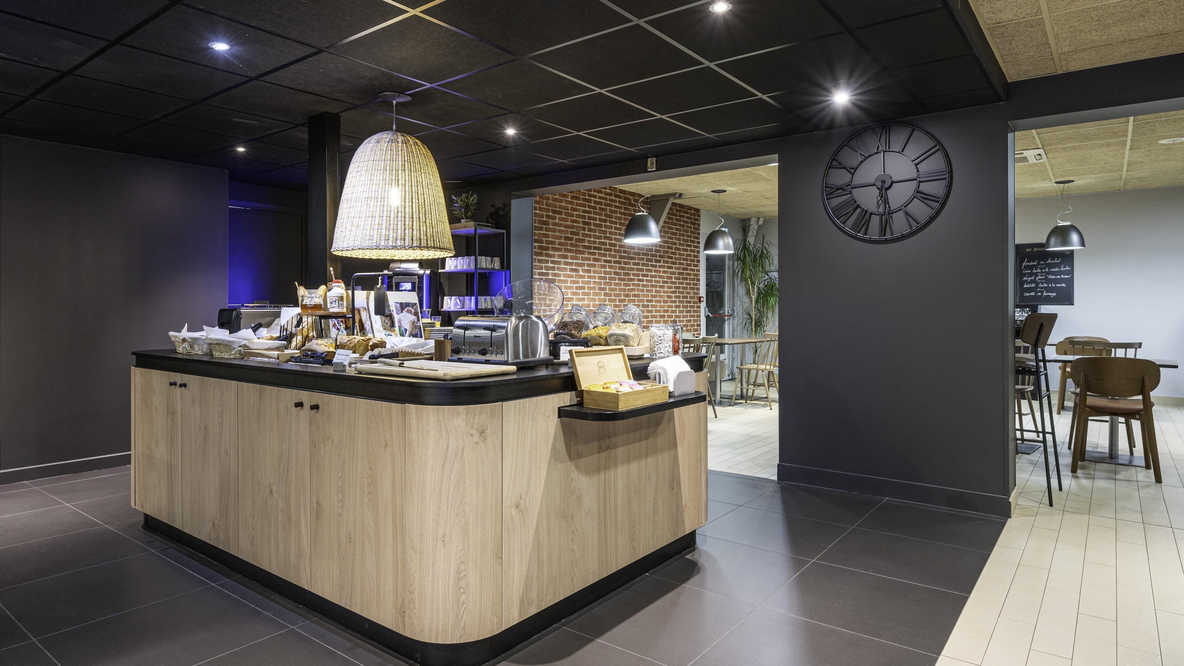 Un café moderno con mostrador de madera, un reloj grande y una pared de ladrillo.