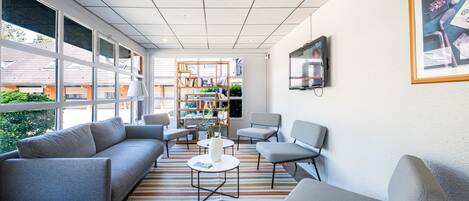 Una sala de estar moderna con un sofá, sillas, una mesa de centro y una estantería.