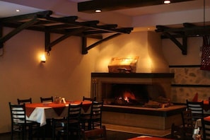 A cozy restaurant with a fireplace, wooden beams, and tables set for dining.