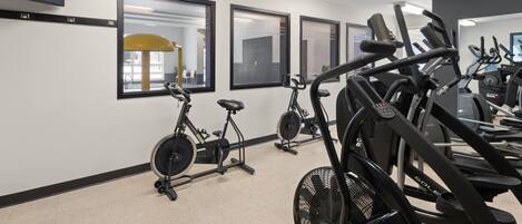 Ein Fitnessraum mit Ergometer, Laufbändern und einer Spiegelwand.