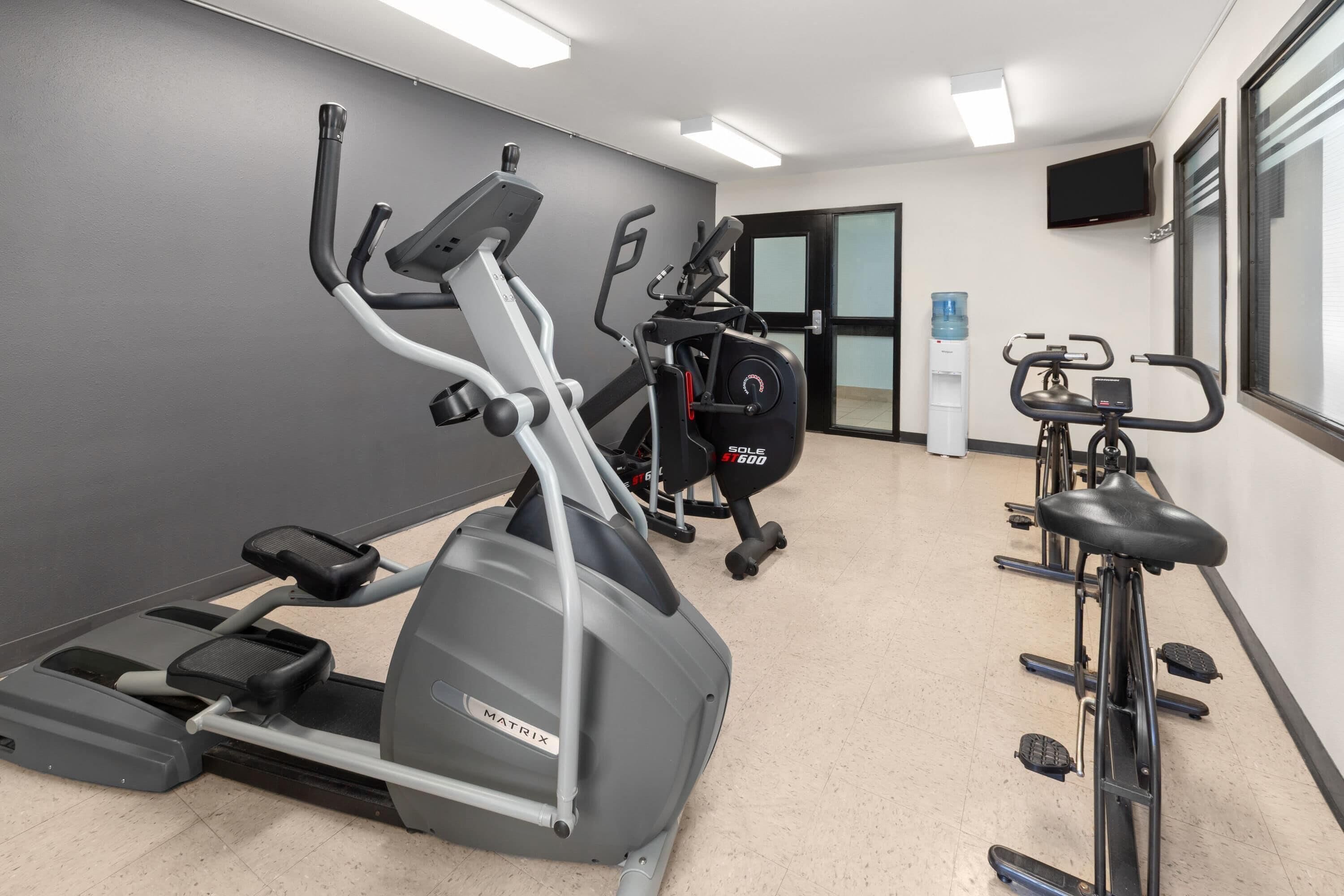 Une salle de sport équipée de tapis de course, de vélos elliptiques et d’un vélo d’appartement.