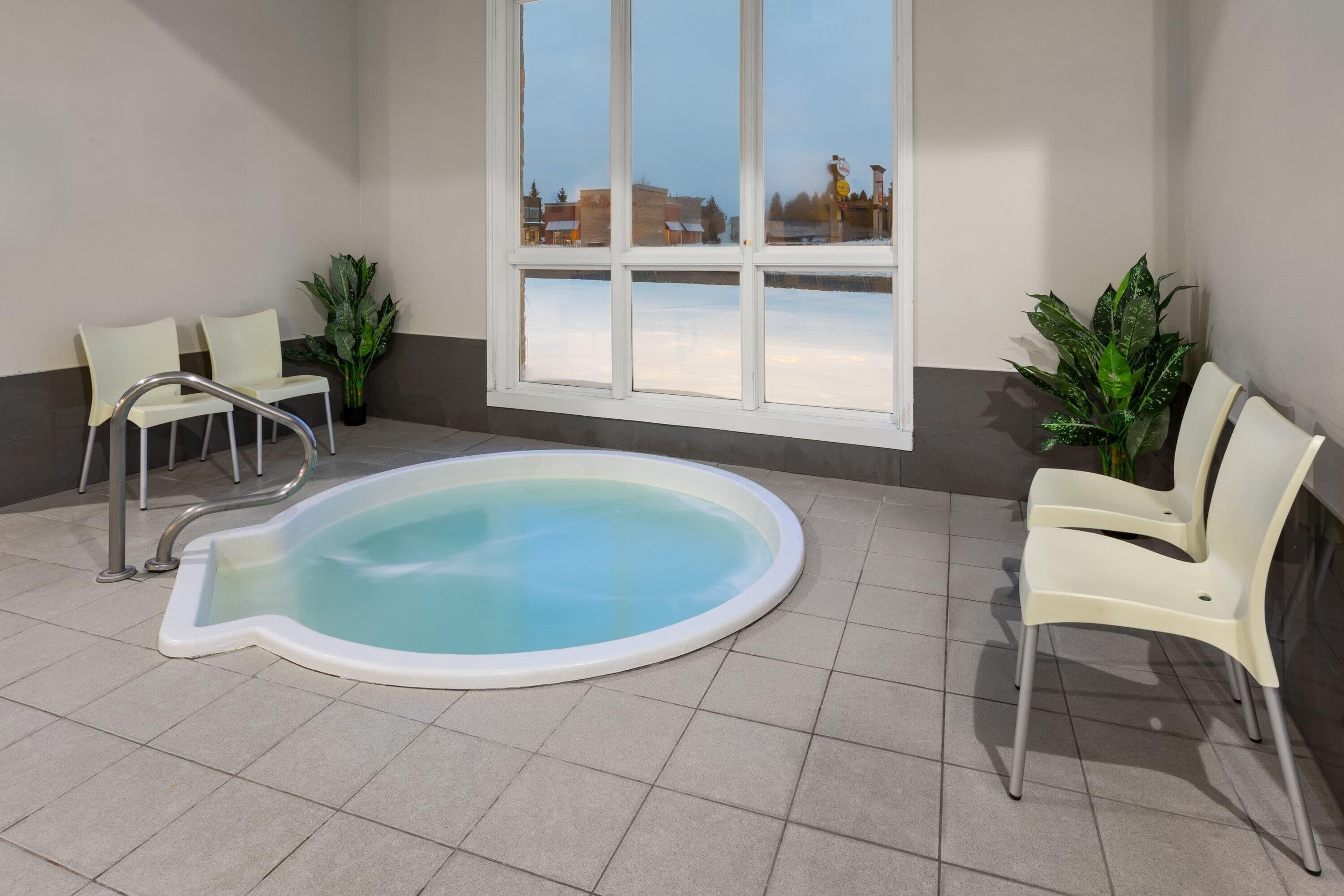 Ein Poolbereich mit Whirlpool, Stühlen und Topfpflanzen.